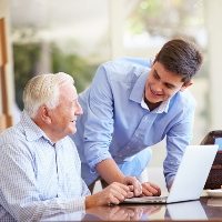 Teenage Grandson Helping Grandfather With Laptop